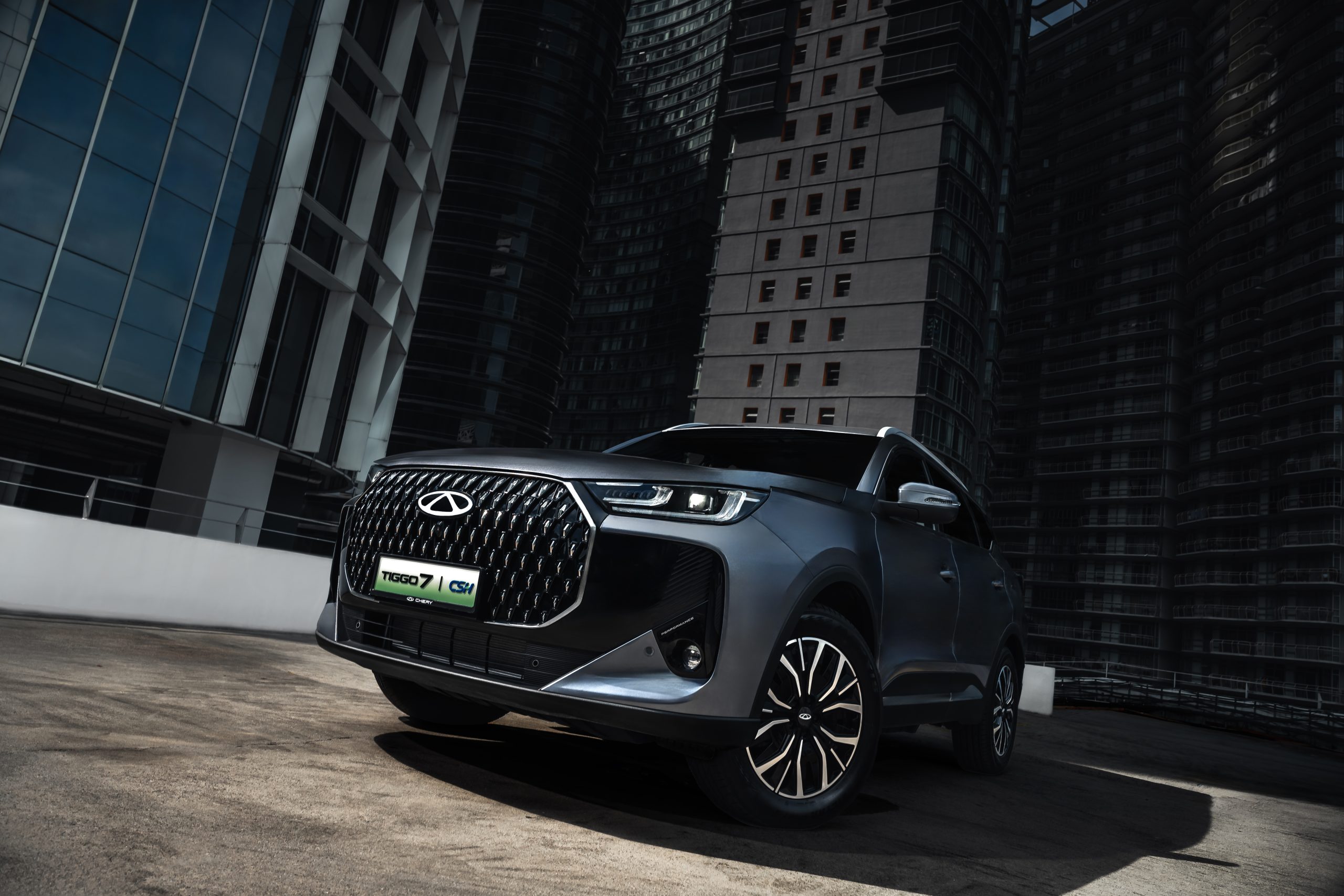 Chery Tiggo 7 PHEV — side three-quarter view beside a lake with mountains and wind turbines