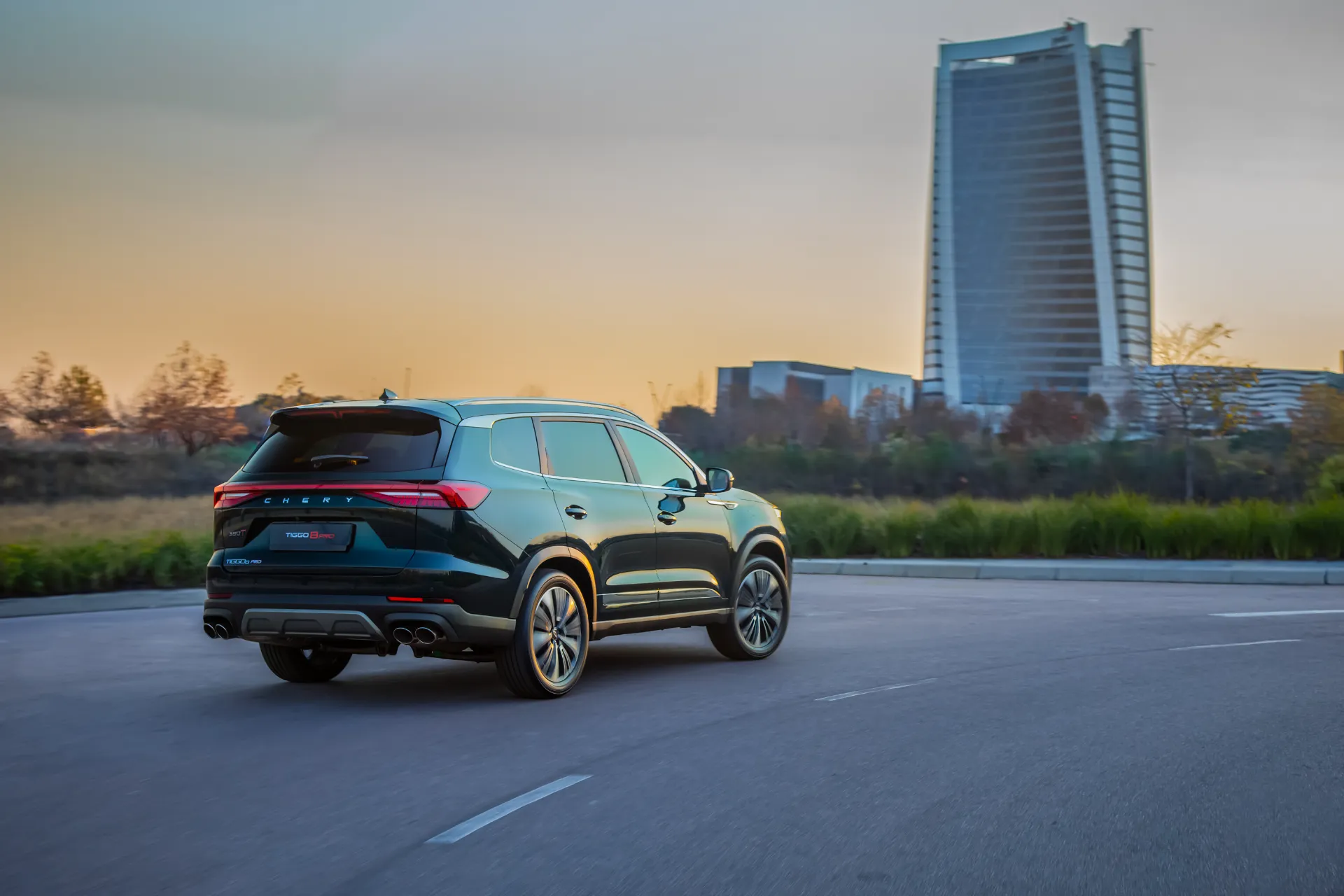 Chery Tiggo 8 Pro — rear three-quarter view at sunset with city skyline