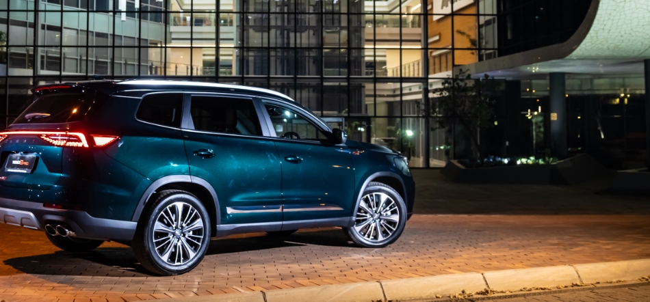 Chery Tiggo 8 Pro — rear three-quarter view outside a modern glass building at night